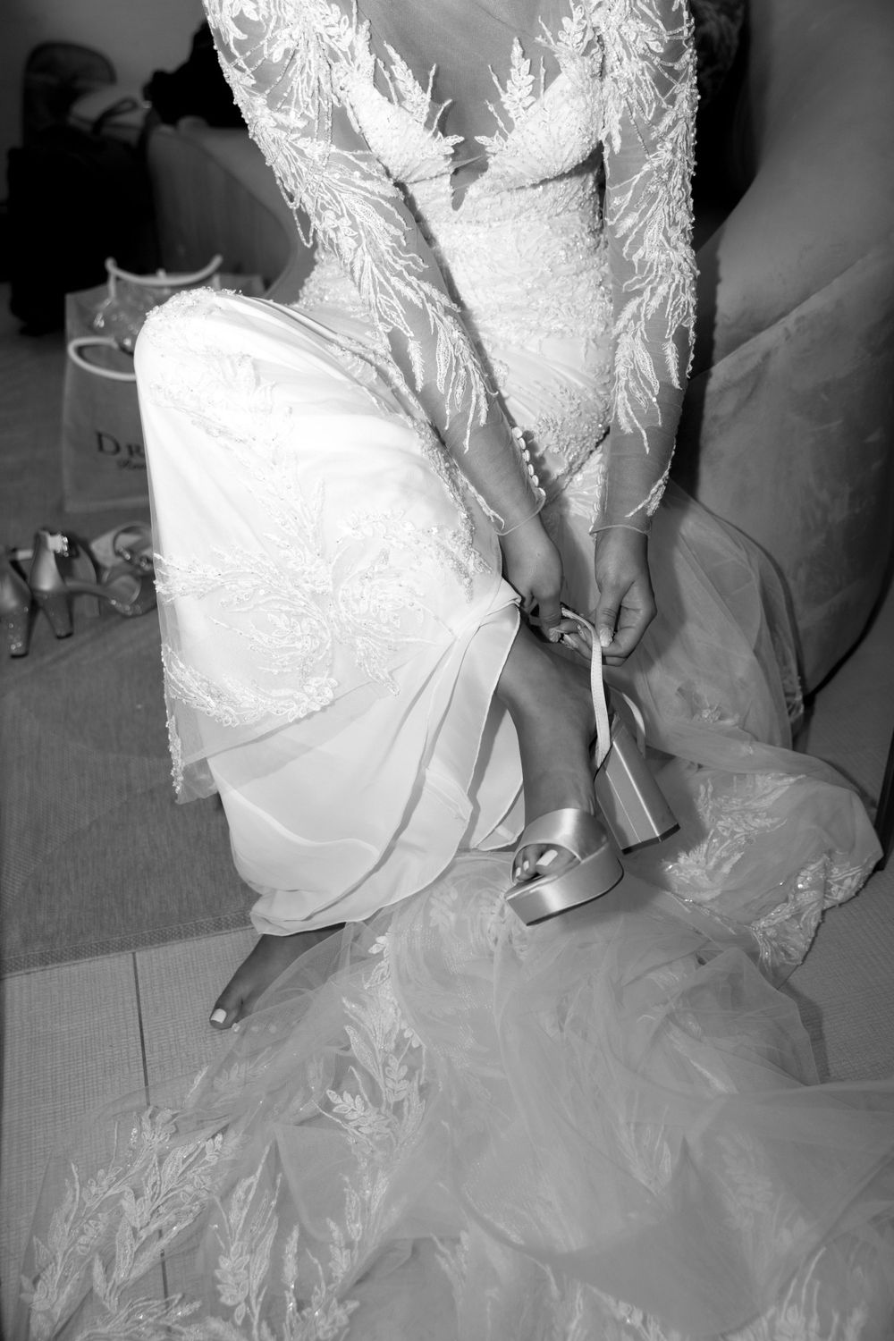 Close up of white wedding dress and silver heels being put on.
