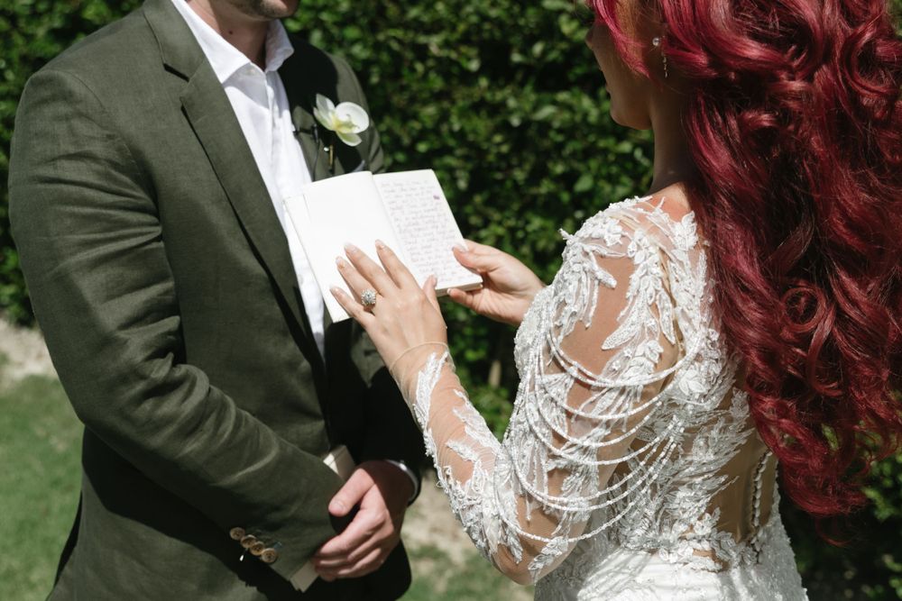 Wedding couple exchanging vows in outdoor garden setting.