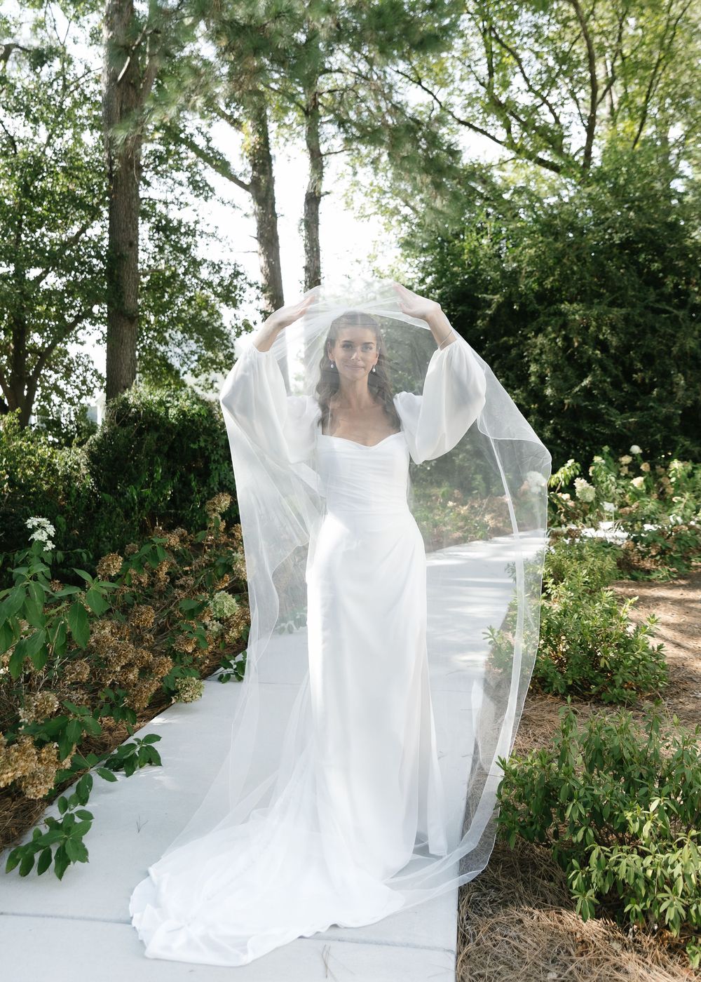 Sequence of flowing white wedding dress and veil photos in a garden setting.
