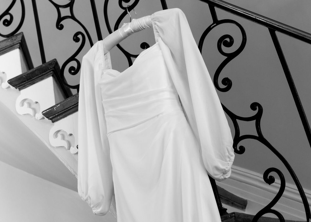 Wedding dresses hanging on ornate iron railings in black and white.