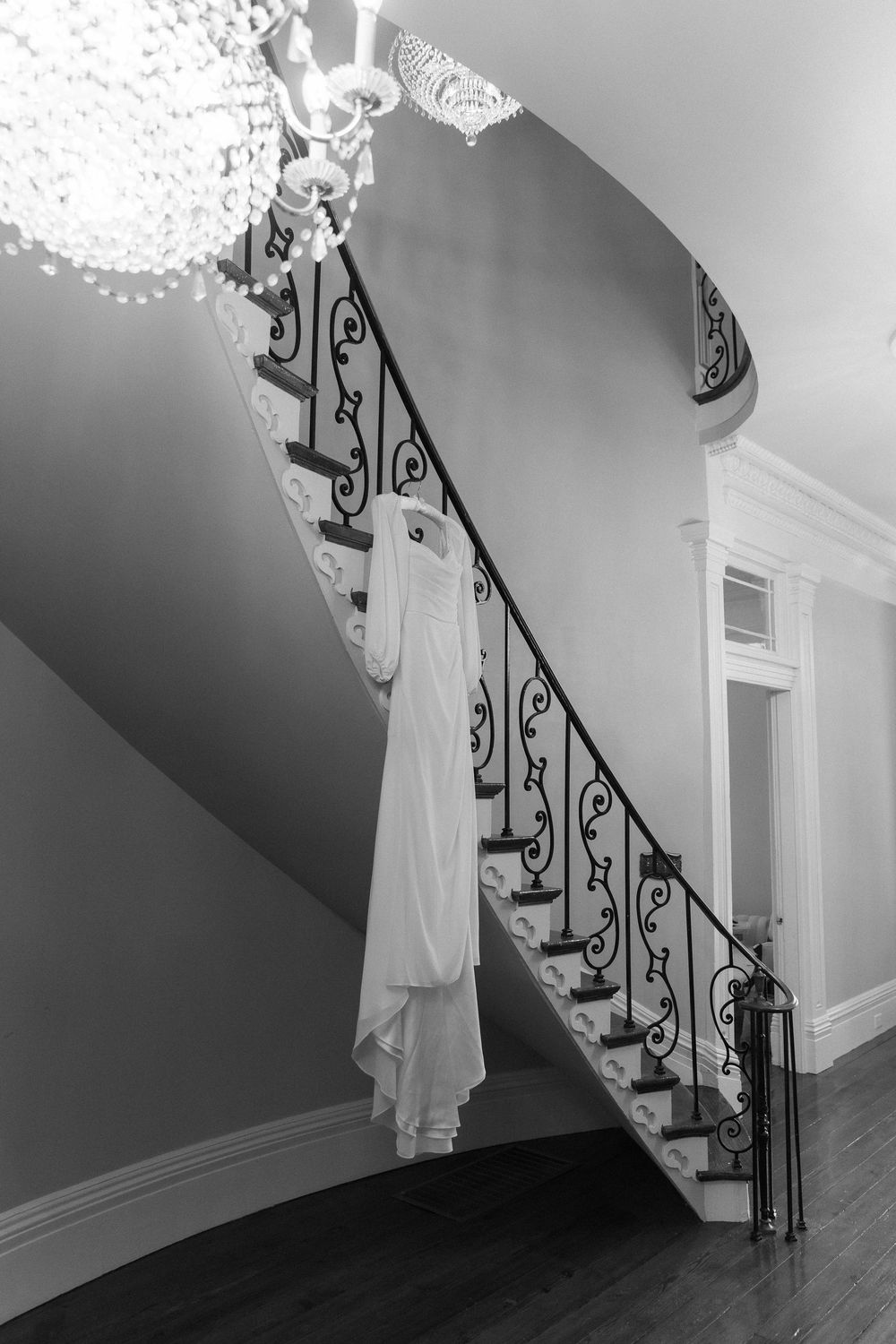 White wedding dress hangs elegantly on ornate staircase railing.