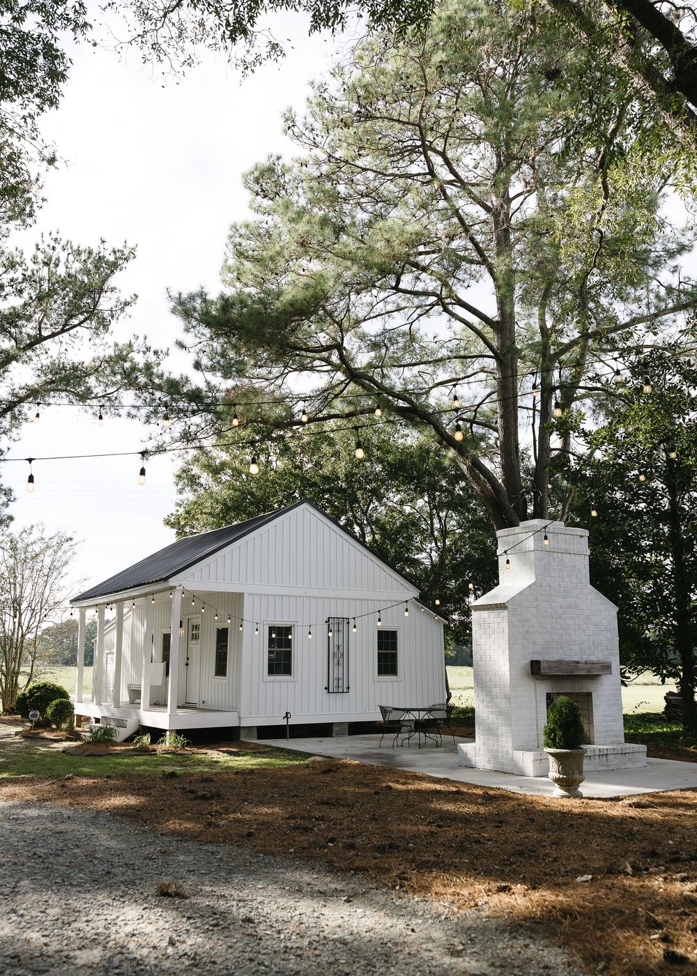 Row of white historic buildings with porches nestled among tall pine trees.