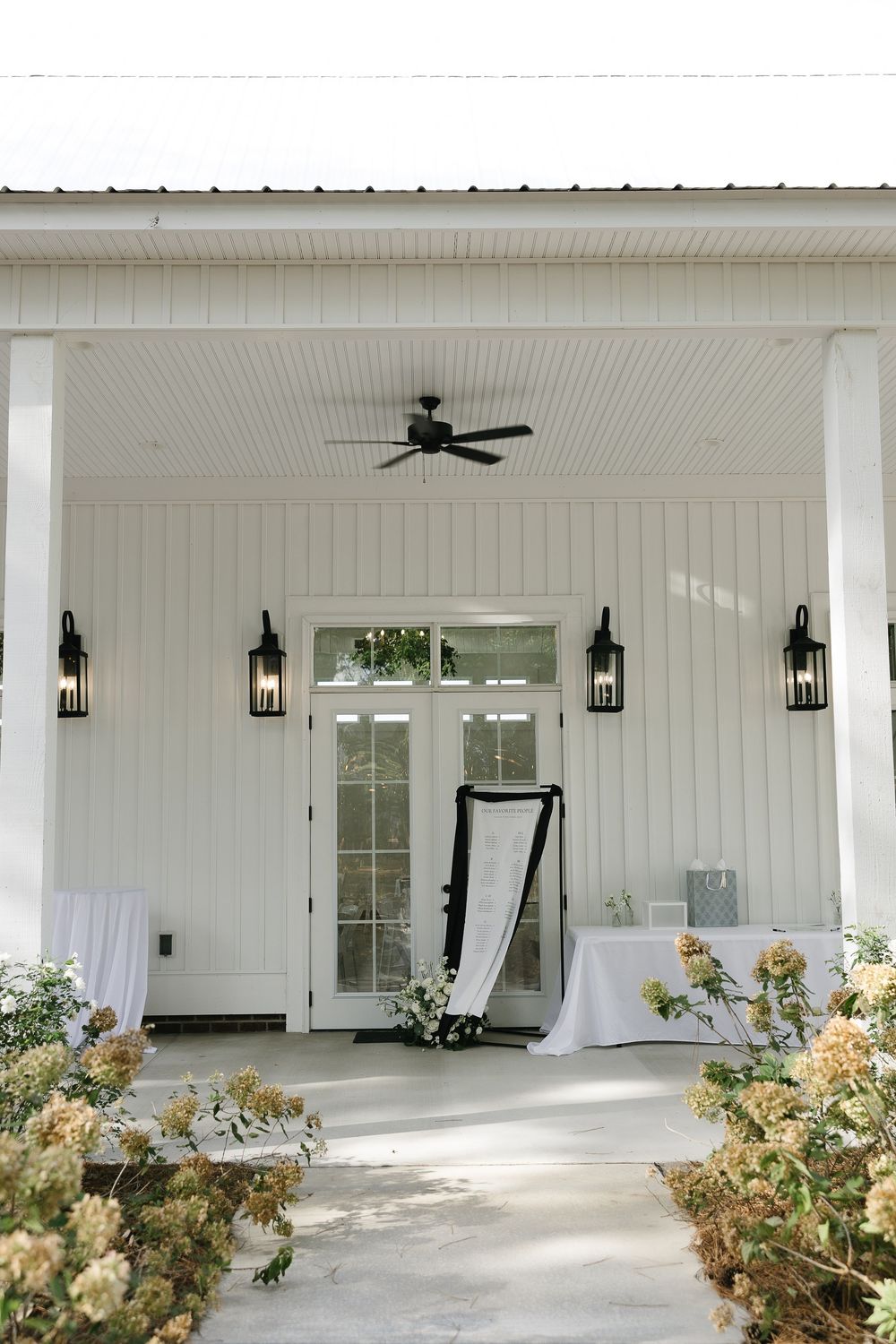 Modern white wedding venue interior with wall sconces and ceiling fan.