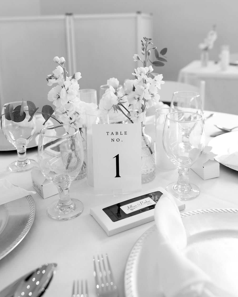 Elegant white table settings with floral centerpieces and table number displays.