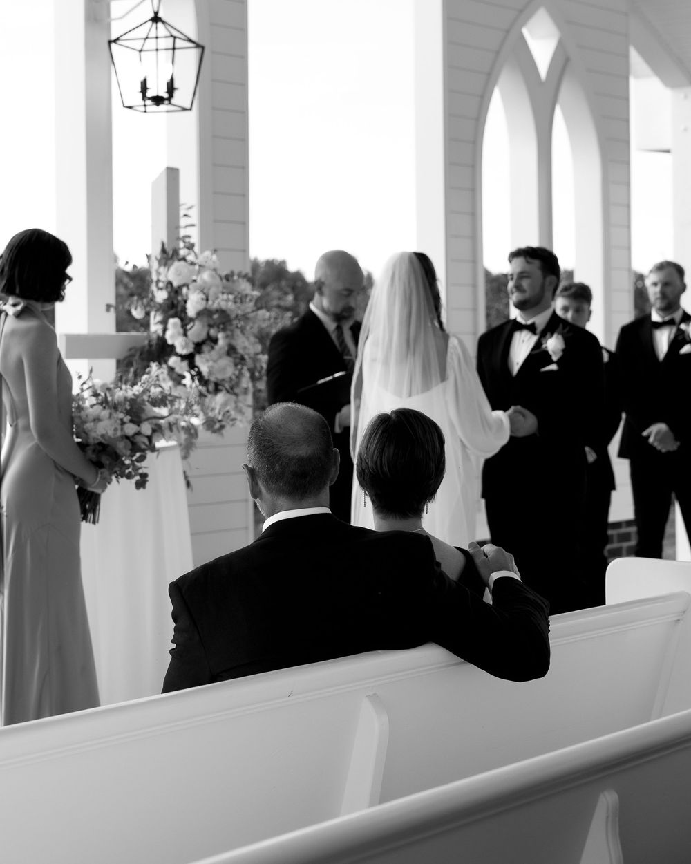 Black and white photo of a wedding ceremony inside a bright, airy chapel.