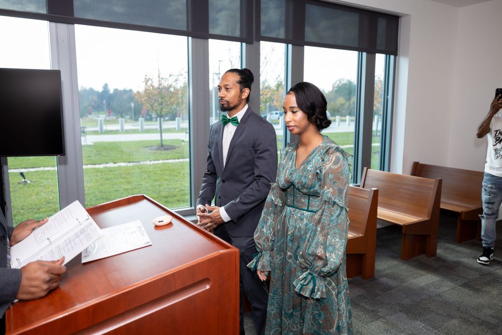 A couple stands in an office setting during what appears to be a civil ceremony.