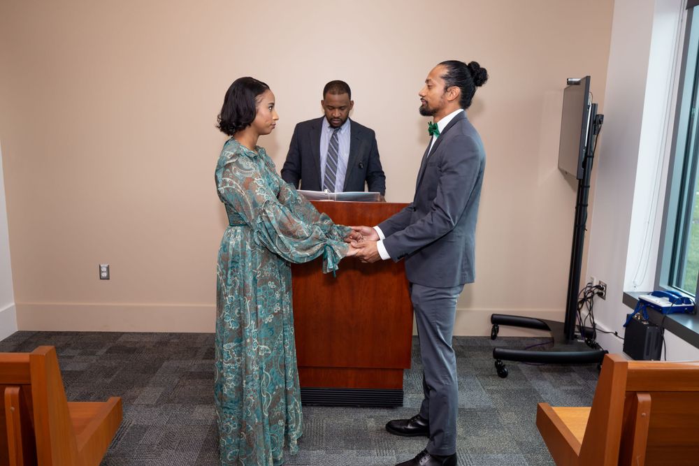 Three people participate in what appears to be a civil ceremony in an office setting.