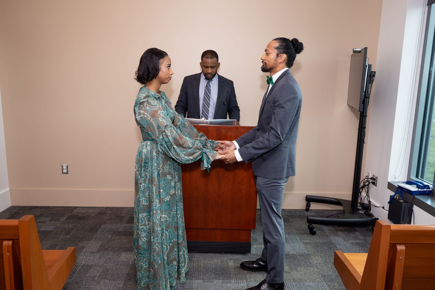 Three people participate in what appears to be a civil ceremony in an office setting.
