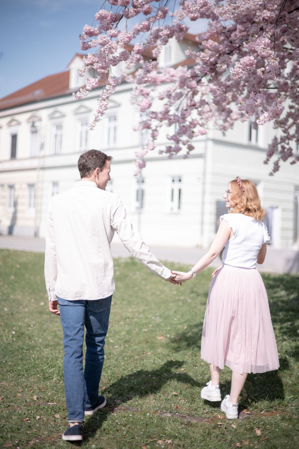 Ein Paar hält sich an den Händen, an einem Frühlingstag unter blühenden Kirschblüten in der Ringstraße in Pfarrkirchen.