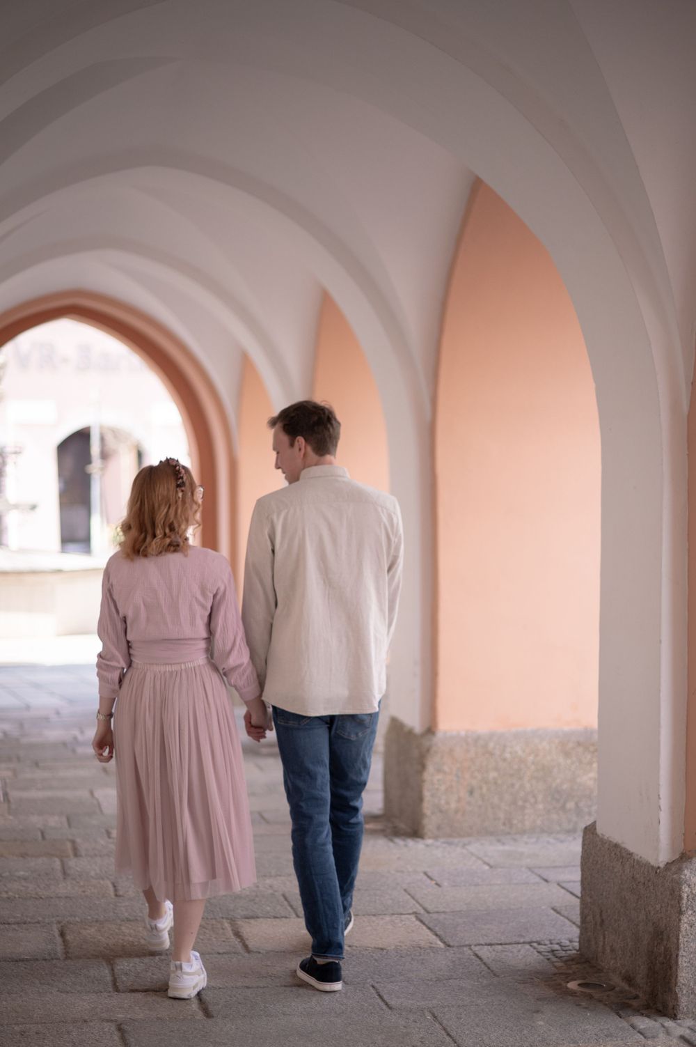 Ein Paar geht Hand in Hand durch einen gewölbten Korridor des Rathauses Pfarrkirchen.