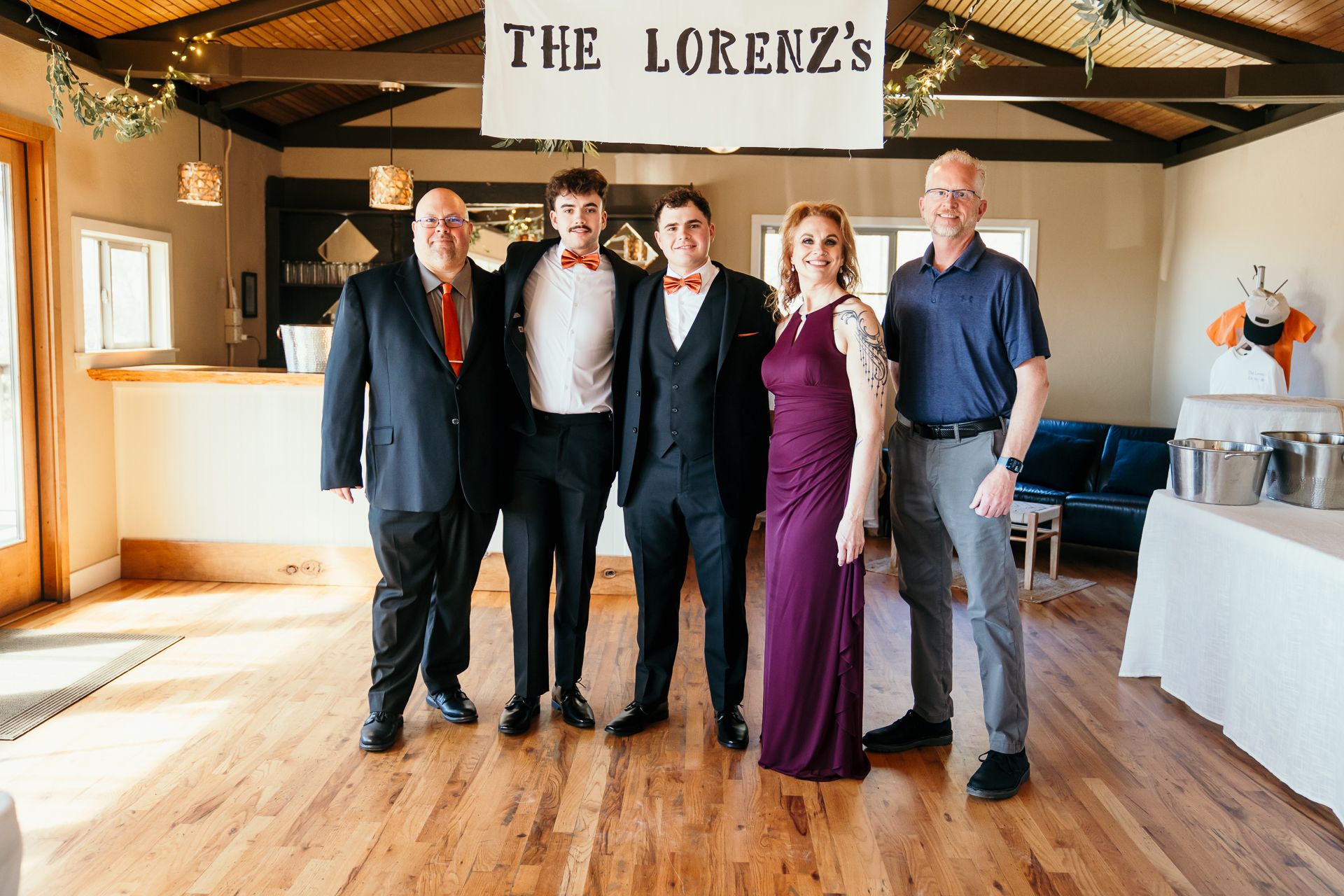 Family photo of six people posing indoors under a The Lorenzs wedding banner.