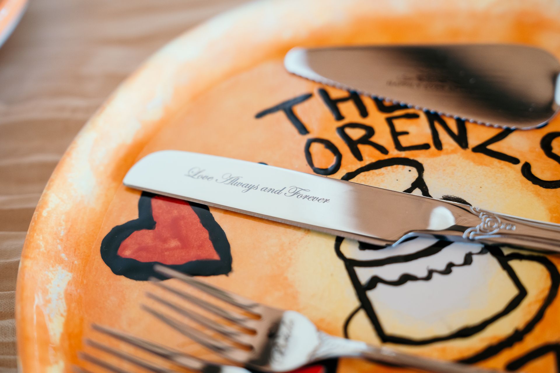Decorative orange plate with The Lorenz name and silverware at wedding reception.