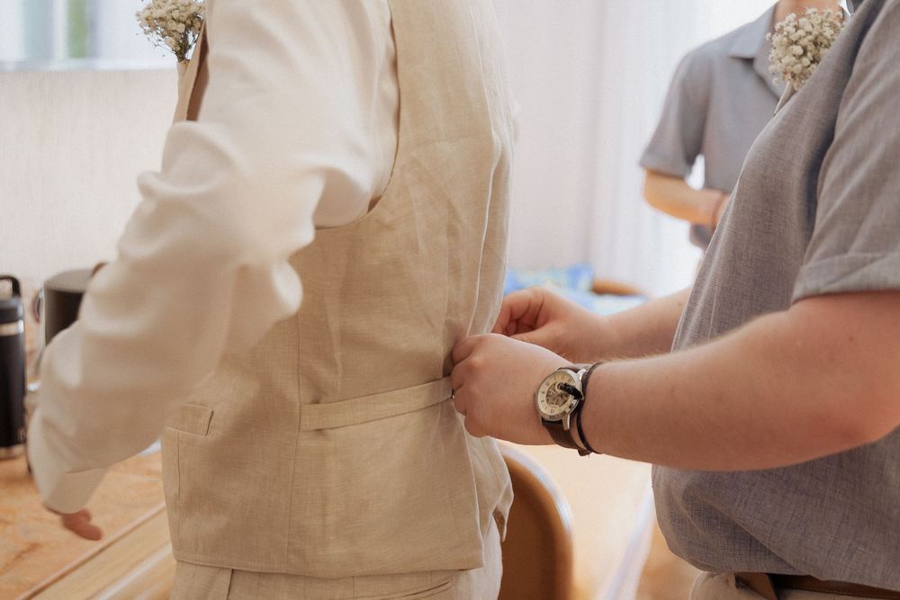 groomsmen does up grooms vest before wedding, getting ready candid moment photography, Mexico destination wedding photographer Cancun