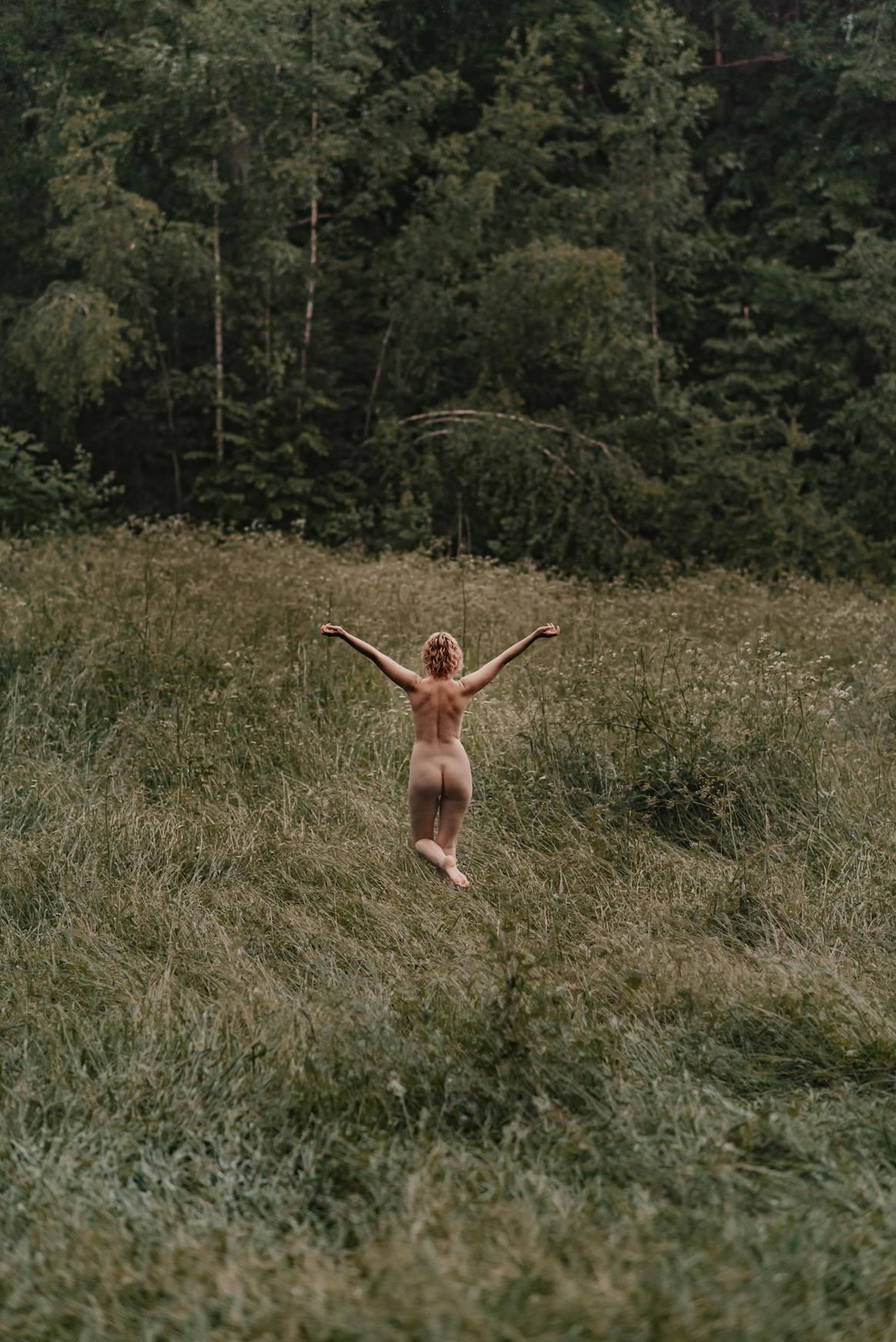 Silhouette jumping joyfully through a tall grassy meadow at sunset.