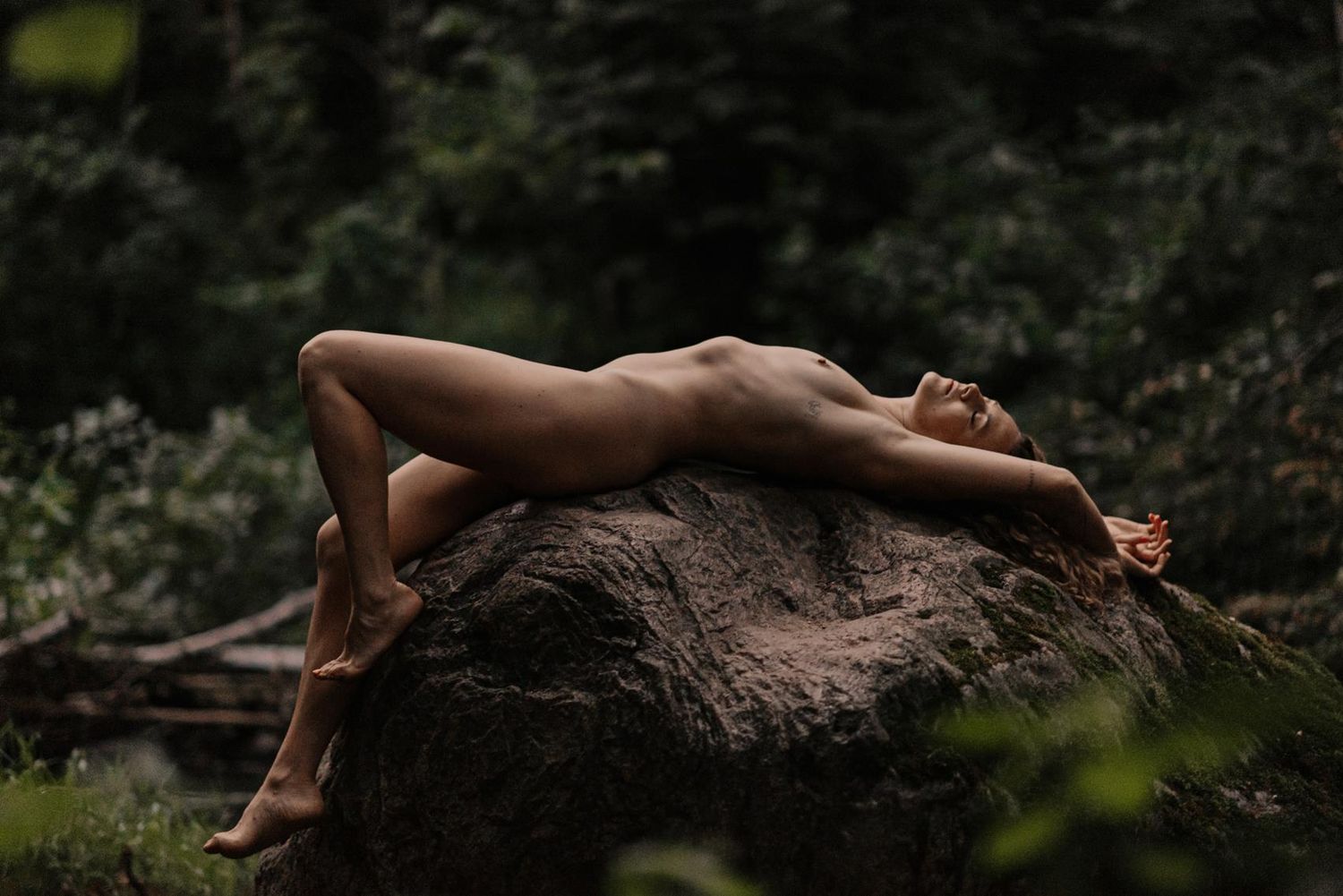 Natural stone formation surrounded by green forest vegetation.