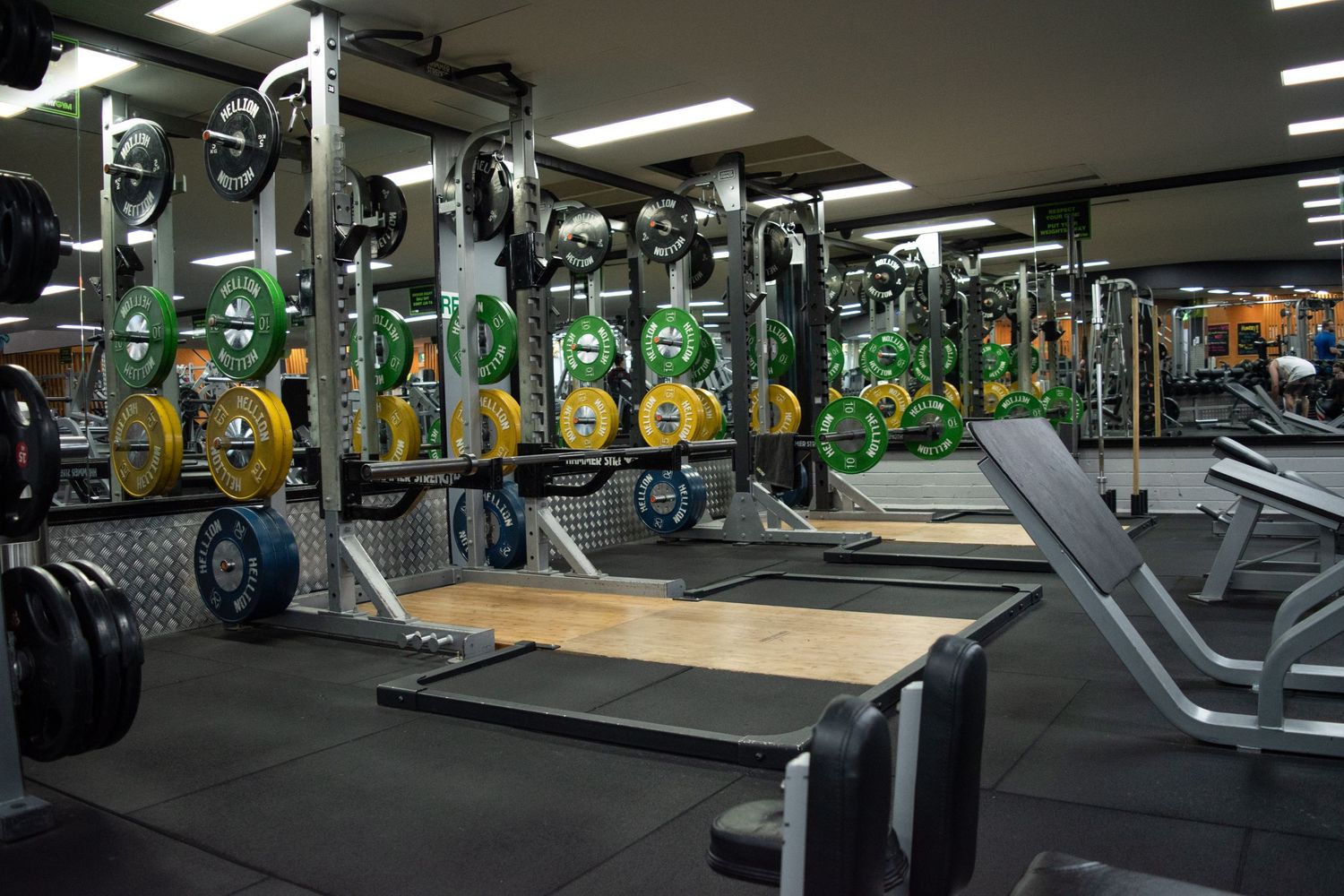 Modern gym interior with rows of weightlifting equipment and barbells.