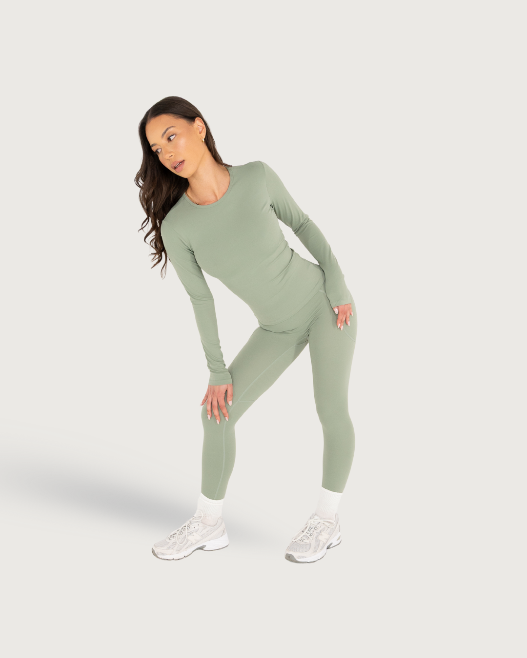 Sage green athletic wear set shown in various poses with long sleeves and fitted pants.
