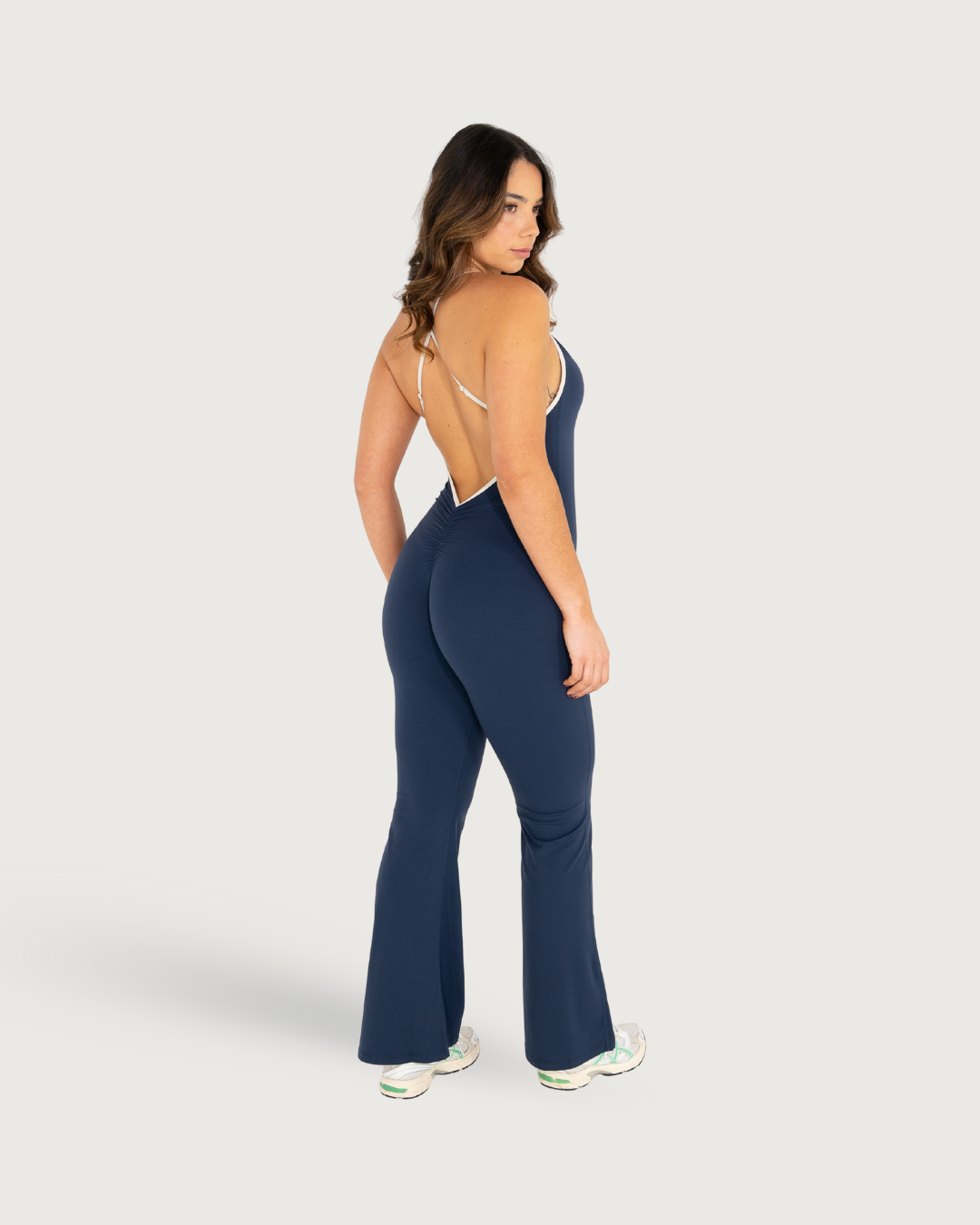 Athletic wear in navy blue featuring a sleeveless jumpsuit with wide legs and white sneakers.
