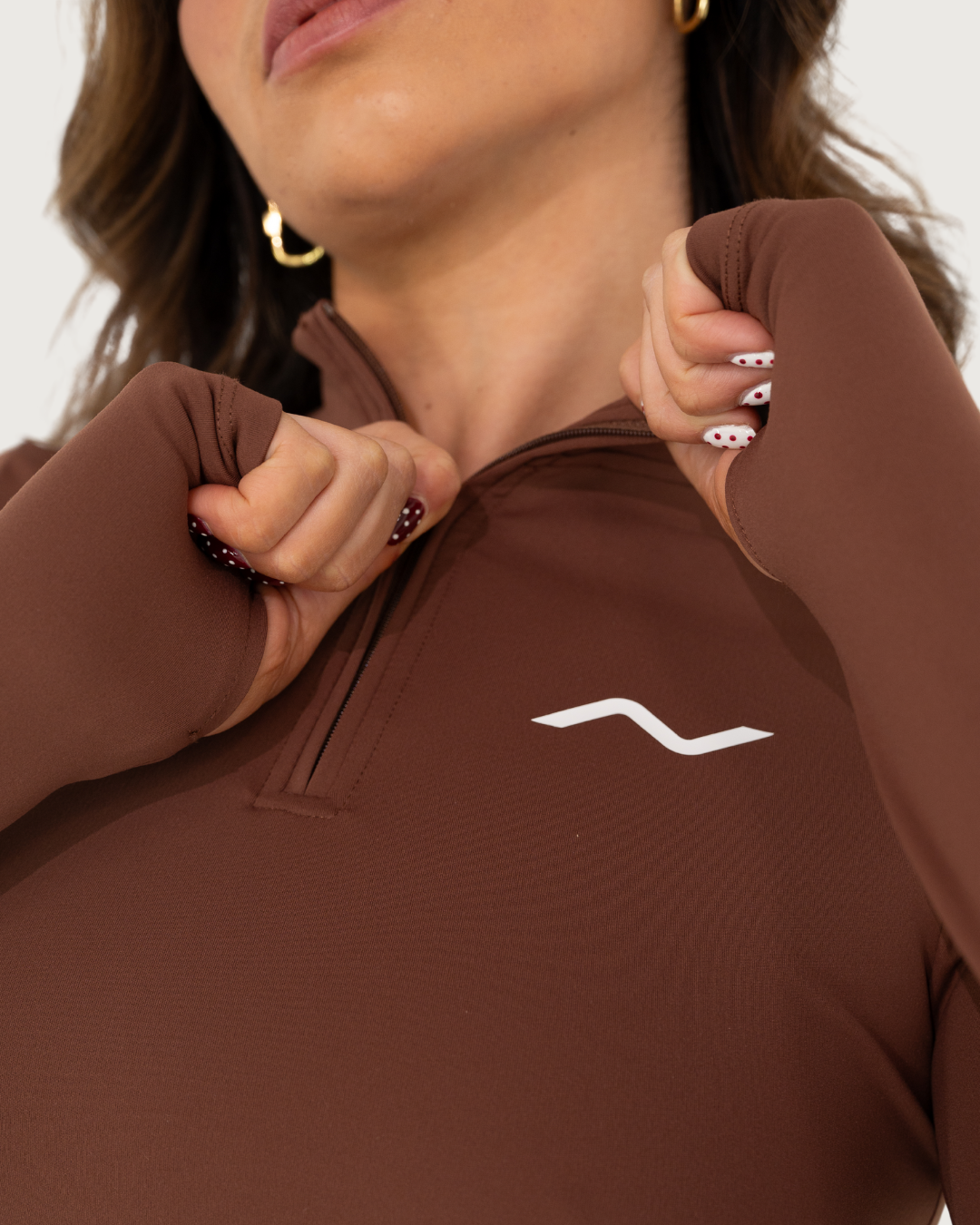 Detail shot of a brown quarter-zip athletic top with white contrast stitching.