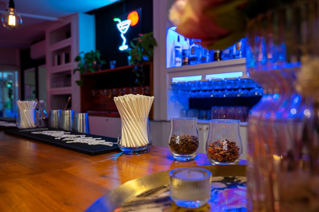 Bar counter with cocktail glasses illuminated by blue neon lights and decorative lighting.