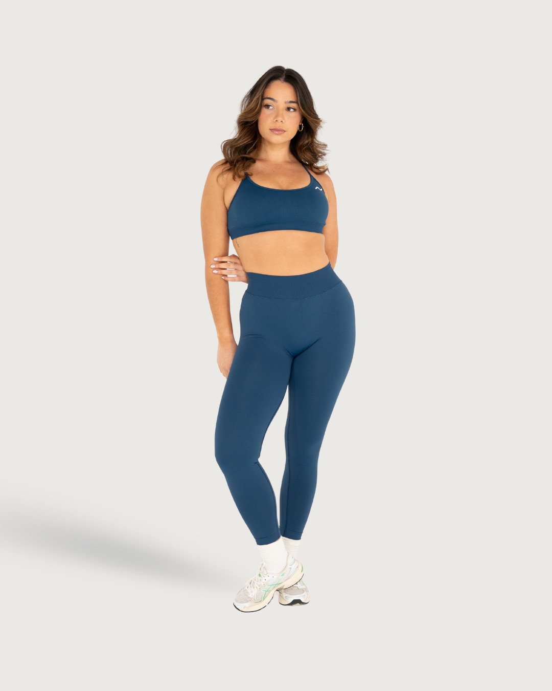 Woman wearing navy blue workout set with sports bra and leggings poses in different positions against white background.