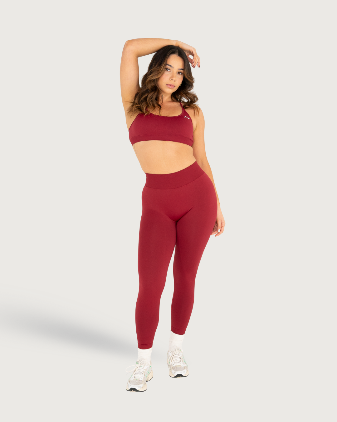 Burgundy athletic wear set featuring a sports bra and high-waisted leggings with white sneakers.