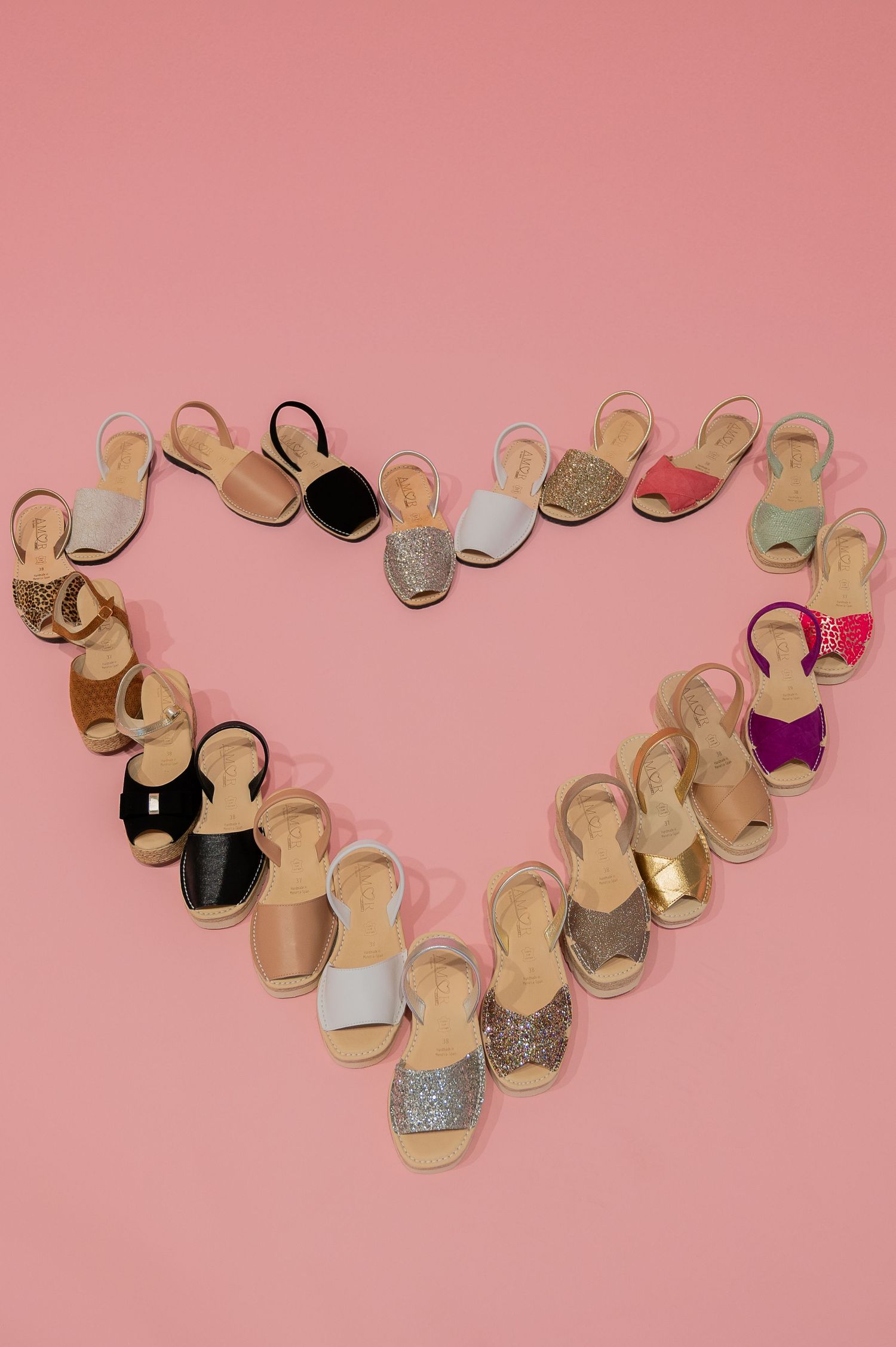 Multiple pairs of ballet pointe shoes in beige and gold tones arranged on a pink background in a curved pattern.
