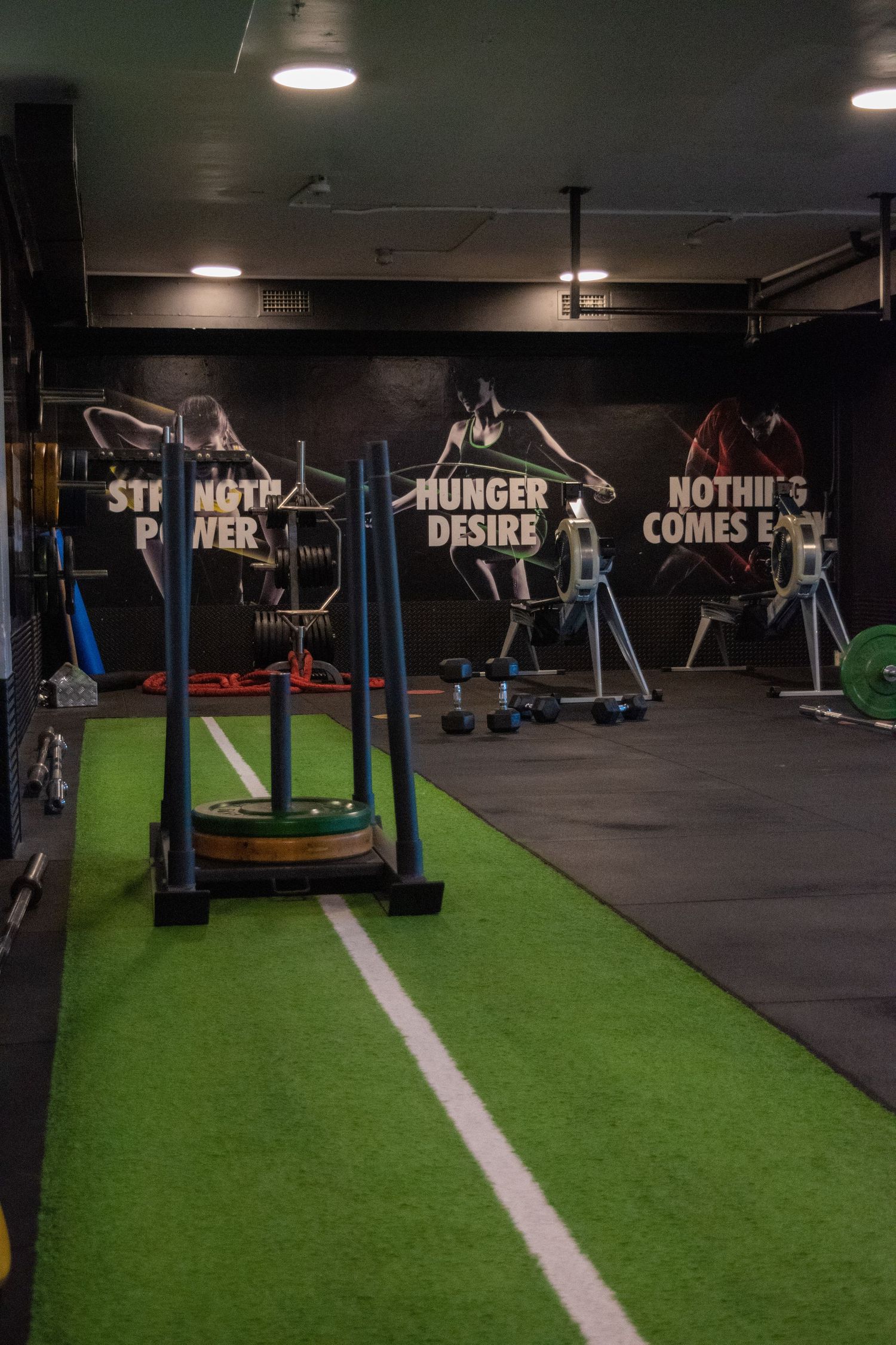 Modern gym interior with artificial turf track and motivational wall quotes.