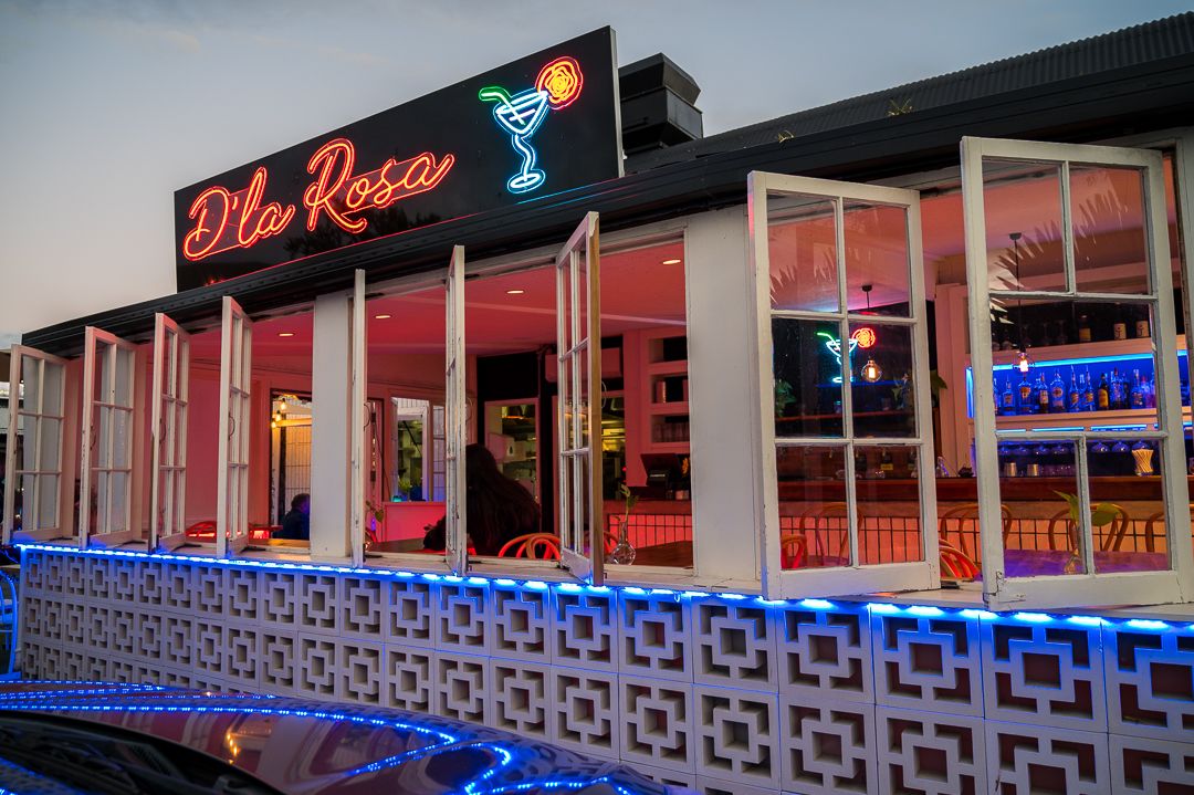Retro neon sign for 'The Room' bar with glowing blue accents at twilight.