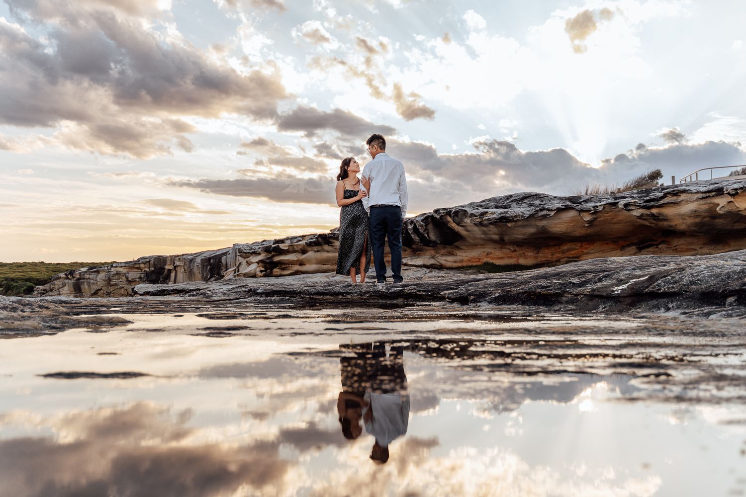 Scenic coastal landscape with rocky formations and dramatic clouds during golden hour.