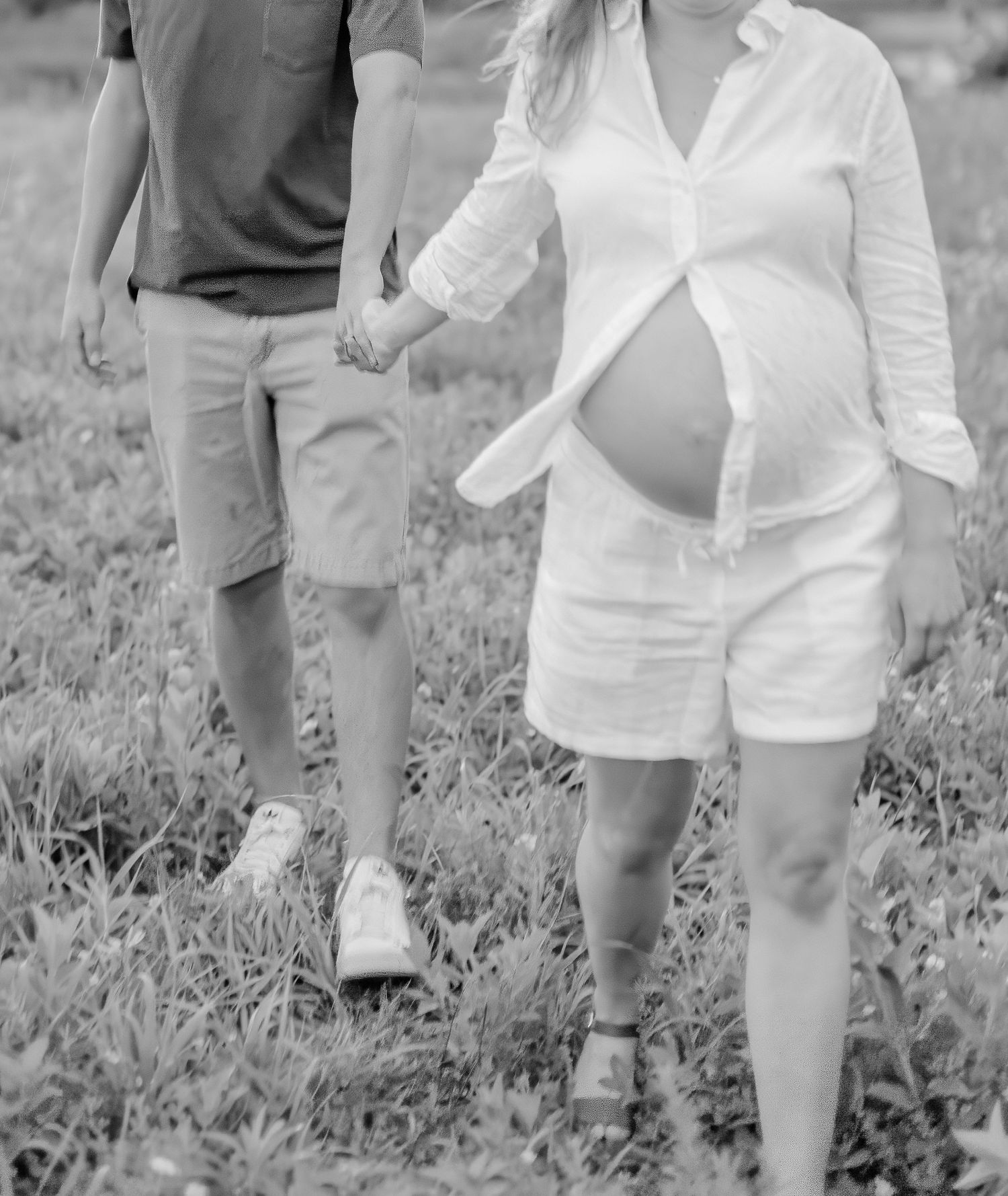 People walking through tall grass field wearing coordinated white and neutral outfits.
