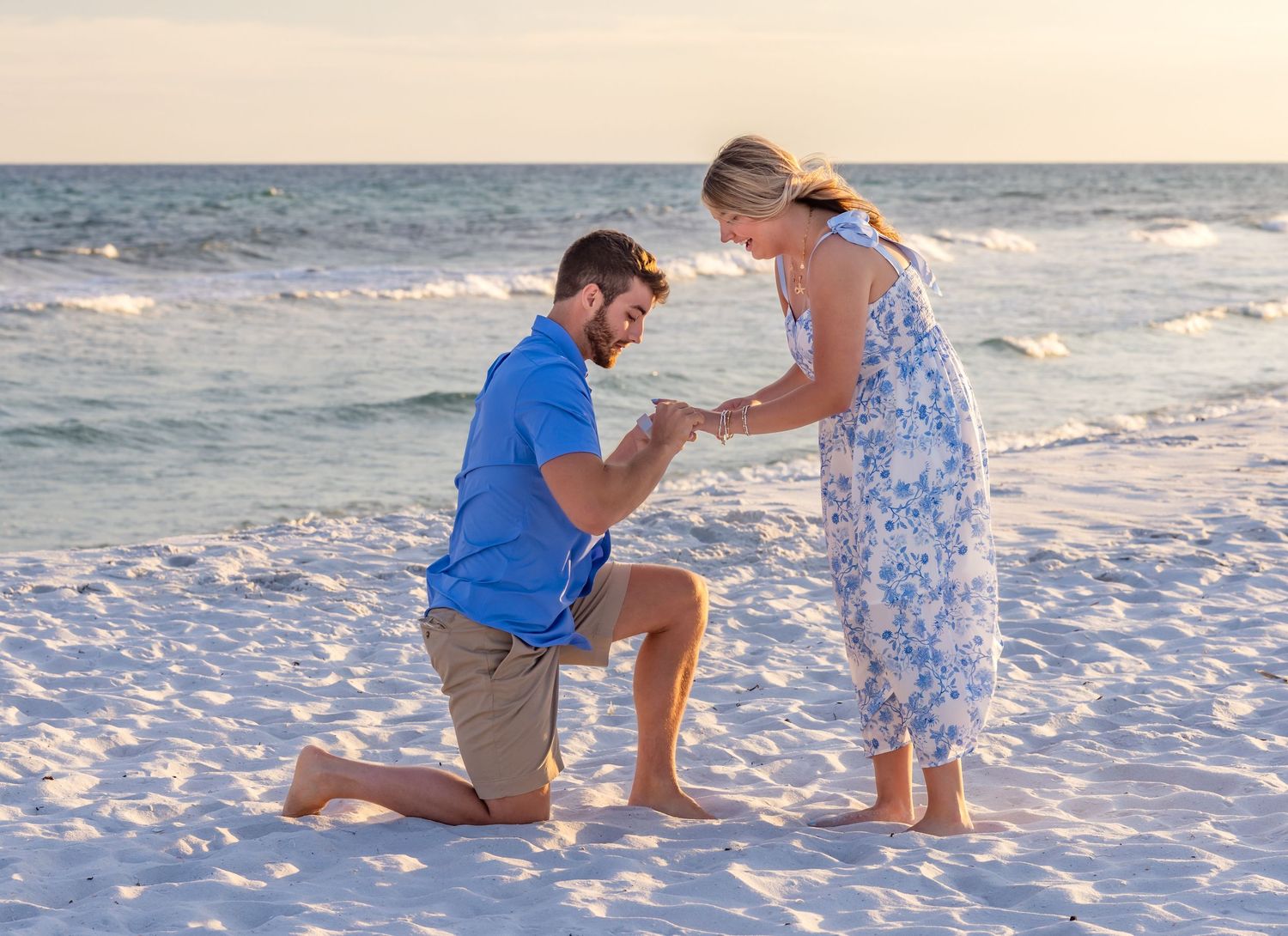 Couple shares romantic beach proposal moment during sunset along ocean shoreline in Florida.