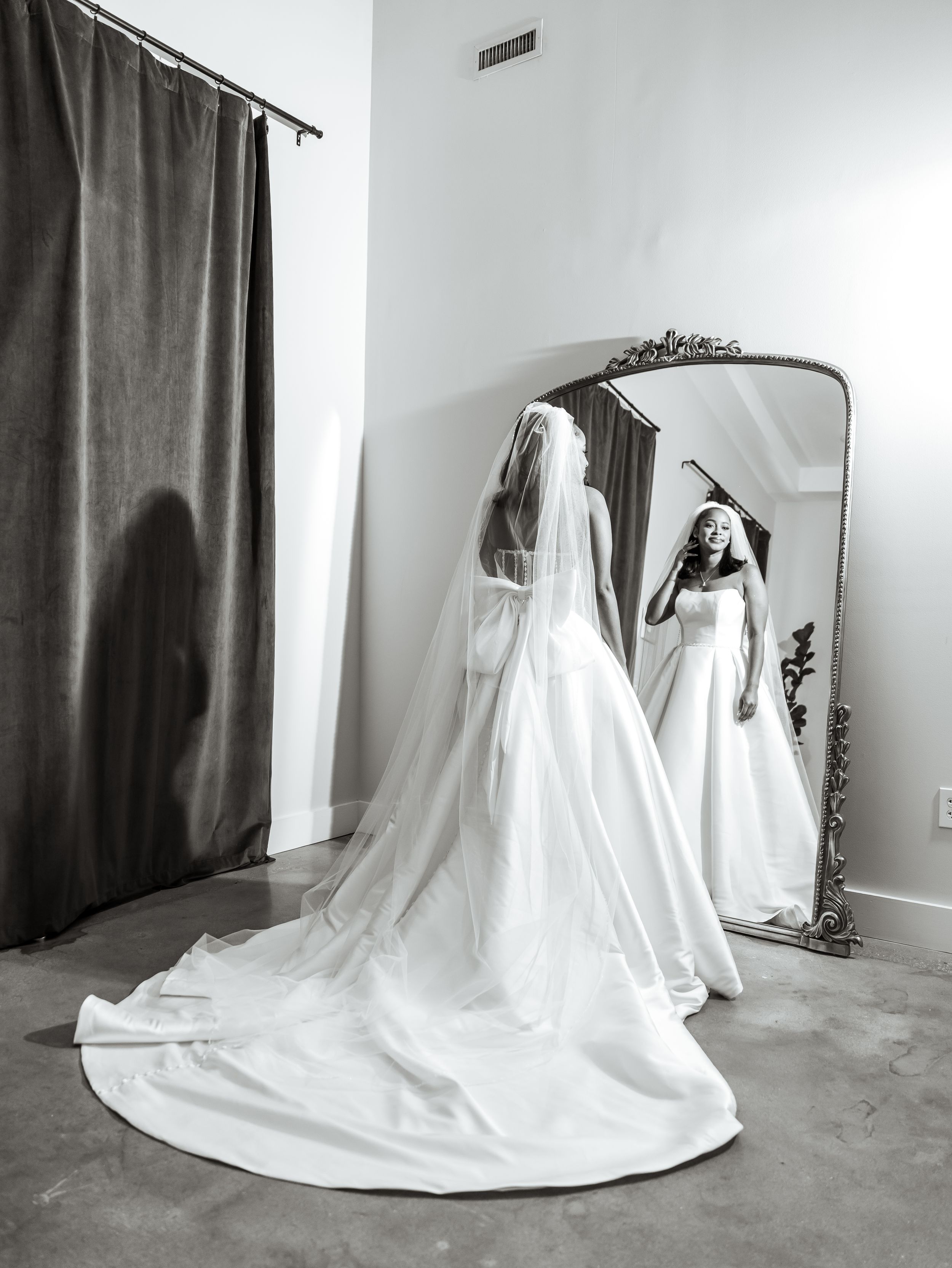 Wedding photographer capturing the bride admiring her wedding dress in Raleigh, nc