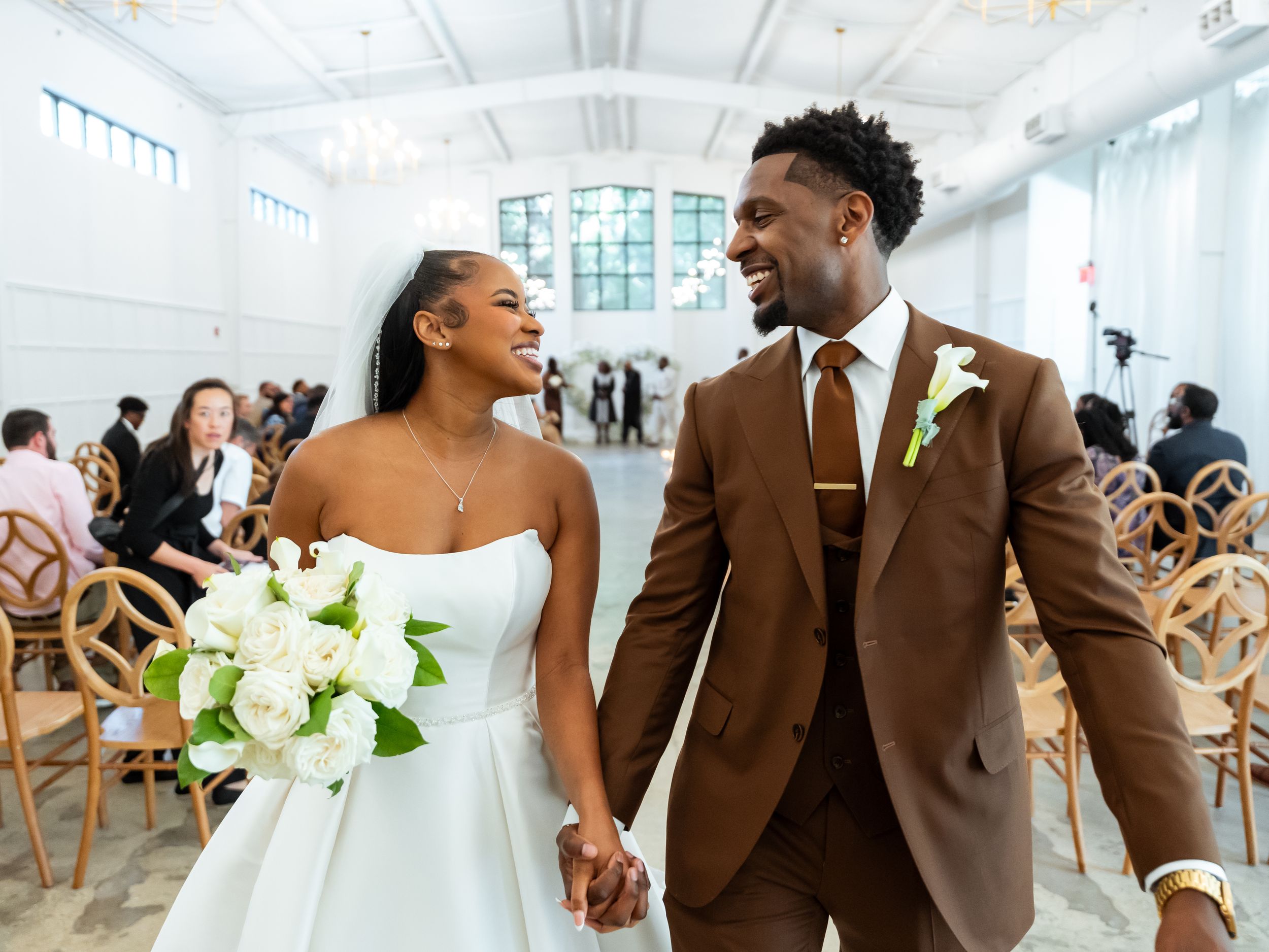 Joyful moment captured in bright wedding venue with wooden chairs in Raleigh Nc