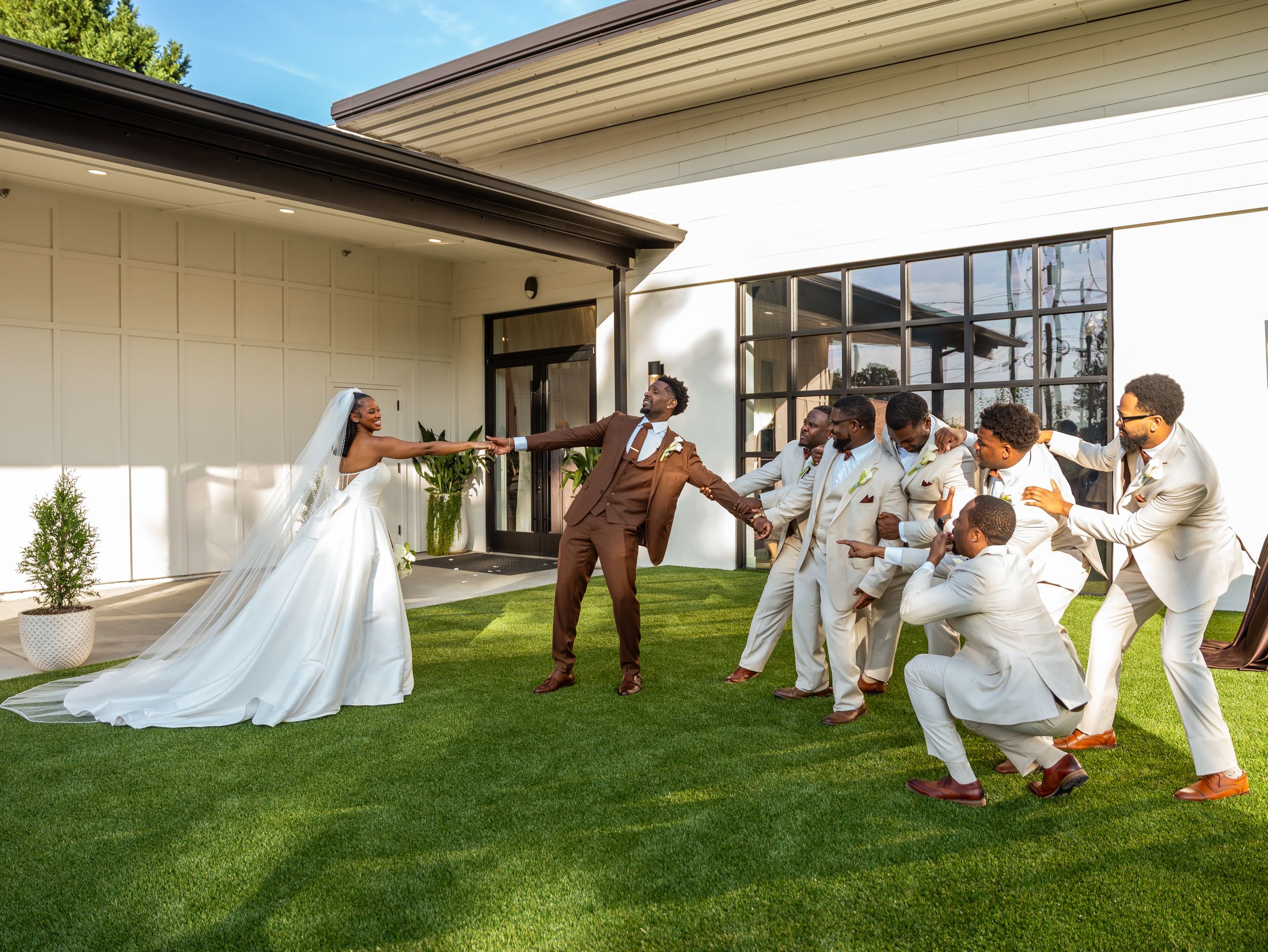 Fun wedding party photo with playful poses on lawn outside venue in north carolina