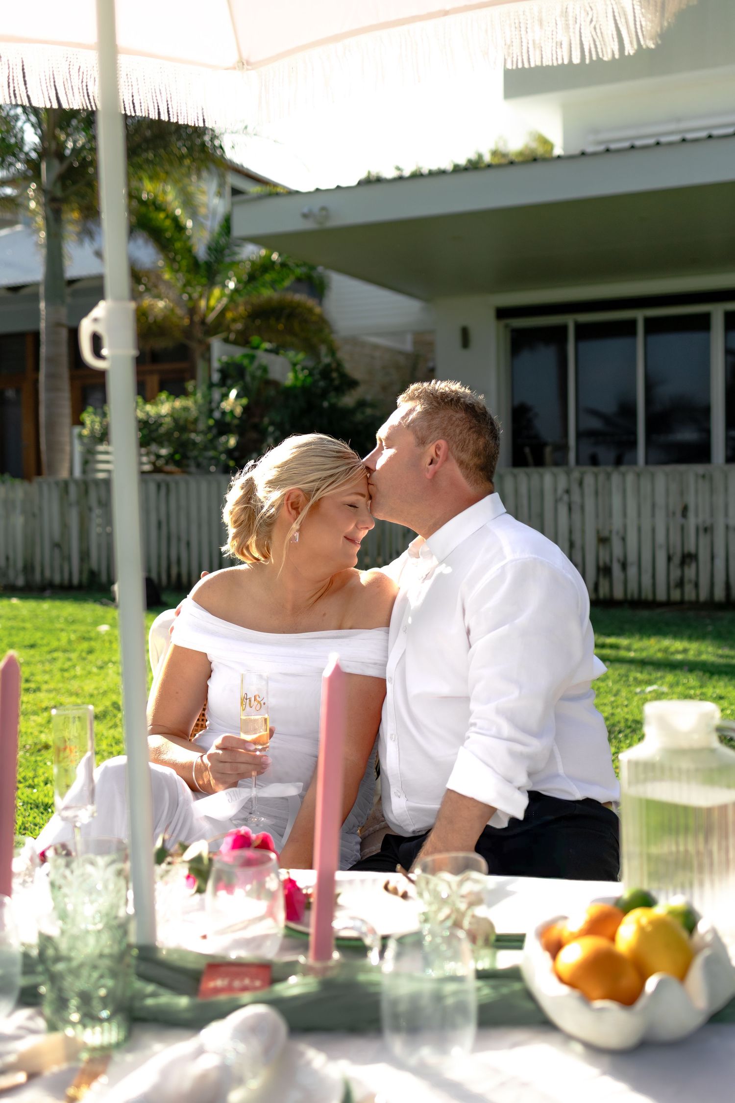 Intimate outdoor wedding reception table setting with white linens and floral arrangements in a garden setting.