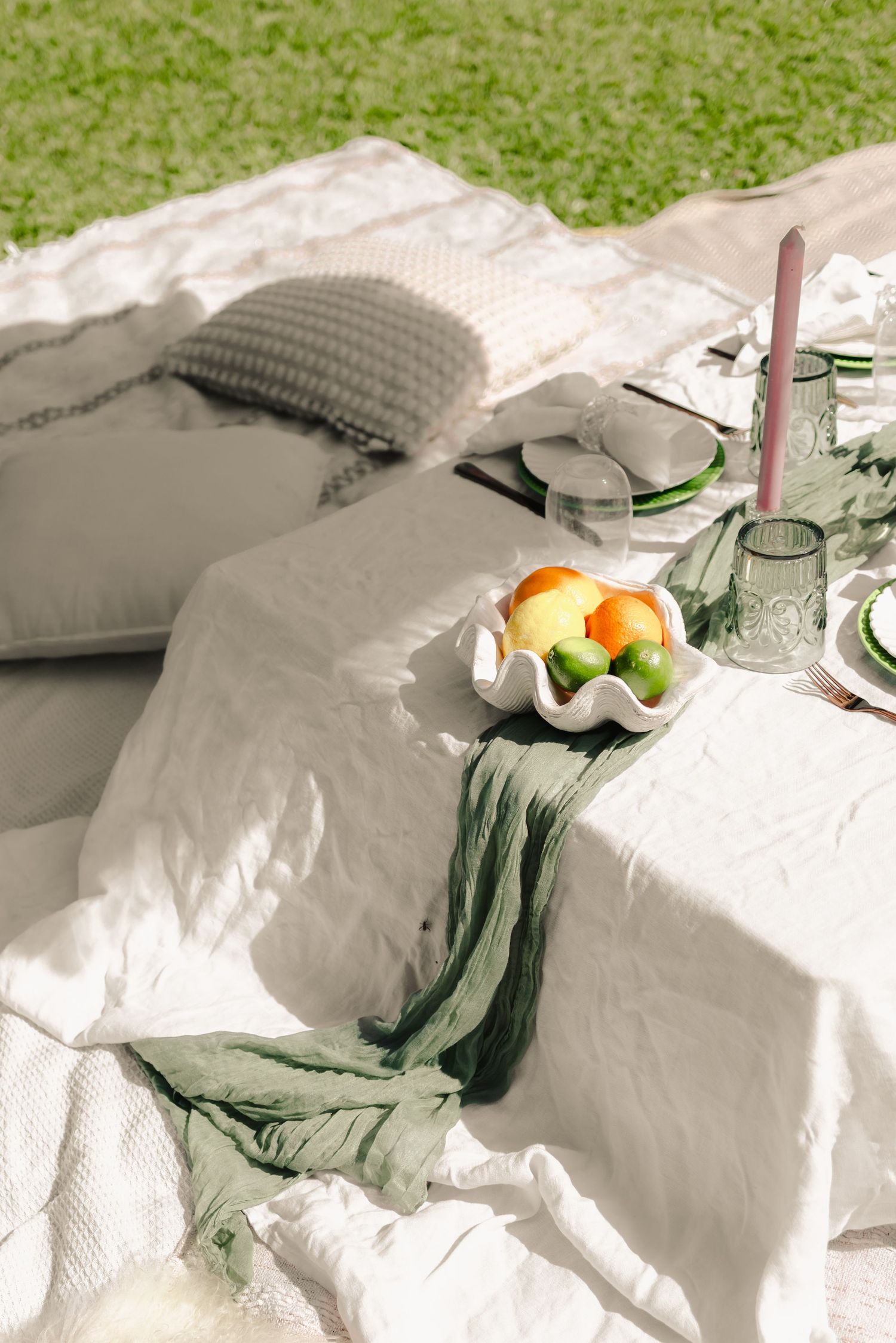 White linen tablecloth with citrus fruits and place settings for an outdoor event.