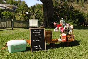 Decorative signs and props arranged on grass for an outdoor wedding ceremony.