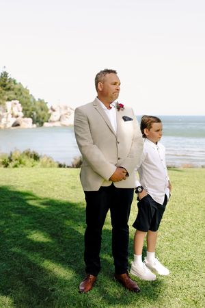 Formal portrait session on a grassy lawn with ocean view in the background.
