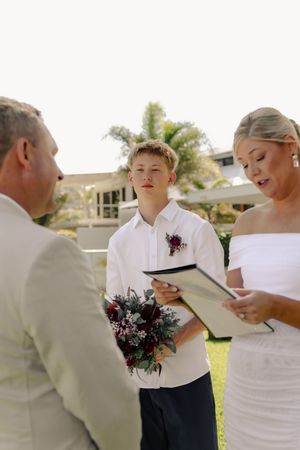 Wedding ceremony participants reading from cards during an outdoor service.