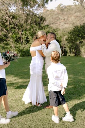 A couple shares their first kiss during an outdoor wedding ceremony.