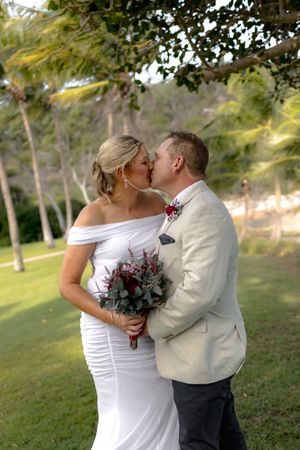 A romantic wedding portrait under palm trees with a beautiful bouquet.