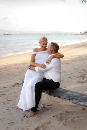 Intimate beach moment captured as couple sits together on sandy shore.