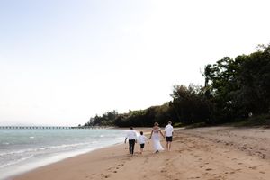 Panoramic beach view with distant figures walking along the shore.