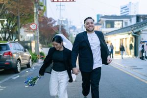 Playful couple photoshoot on a quiet street with modern buildings in the background.