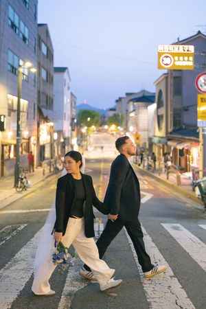 Couple poses on crosswalk during blue hour in a Korean city street.
