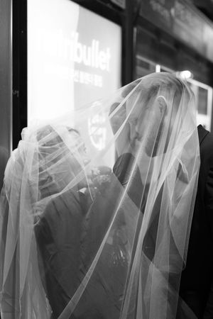 Wedding dresses on display in a store window create an ethereal black and white composition.
