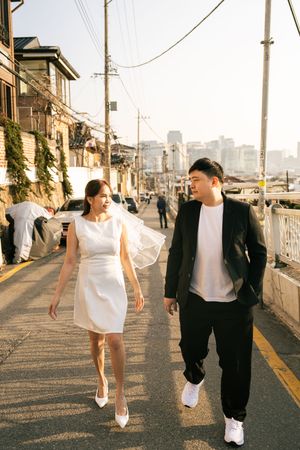 Couple walking casually down sunset-lit street with power lines overhead.