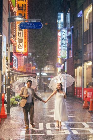 Rainy night photoshoot in bustling Korean city street with neon lights.