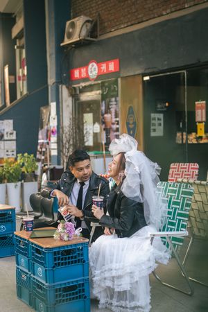 Wedding guests sit at tables with white tulle decorations and blue plastic crates in a casual restaurant setting.